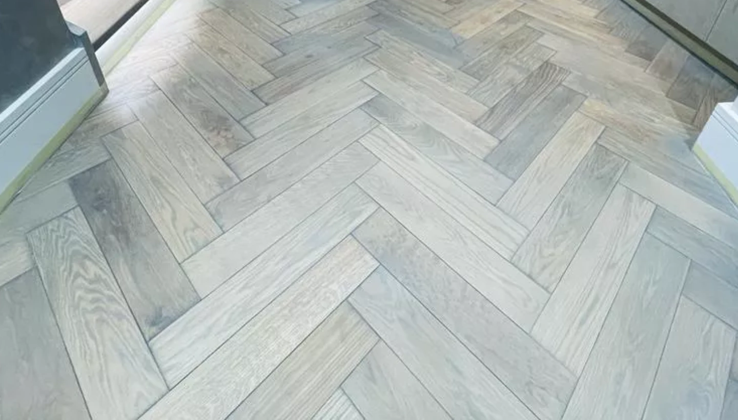 custom grey-stained oak floor in Kensington, meticulously finished in a herringbone pattern to achieve a sophisticated and durable look.