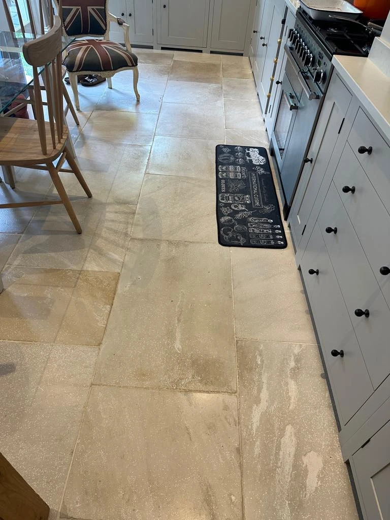 Limestone floor in a Tooting kitchen before cleaning, showing stains and wear