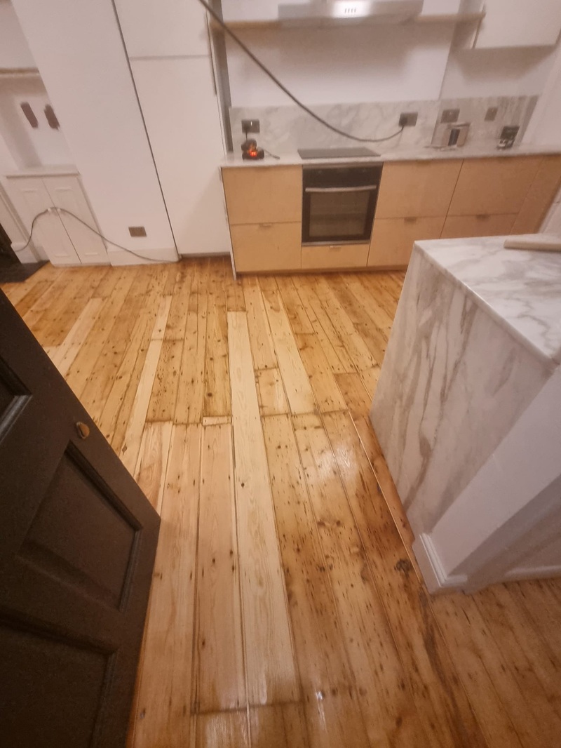Detail of restored pine floorboards near kitchen island in London home