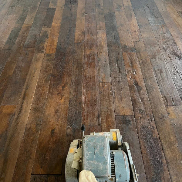 Parquet floor sanding in progress using professional dust-free equipment, revealing the natural wood beneath old finishes.