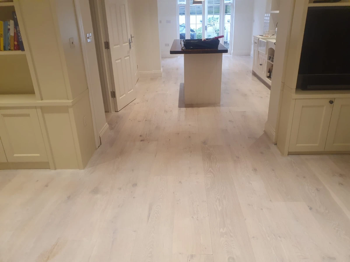 Scandinavian-style whitewashed wooden floor in a modern kitchen and living space in Angel, London, restored to a light, airy finish.