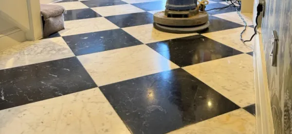 Polishing a black and white marble checkerboard floor.