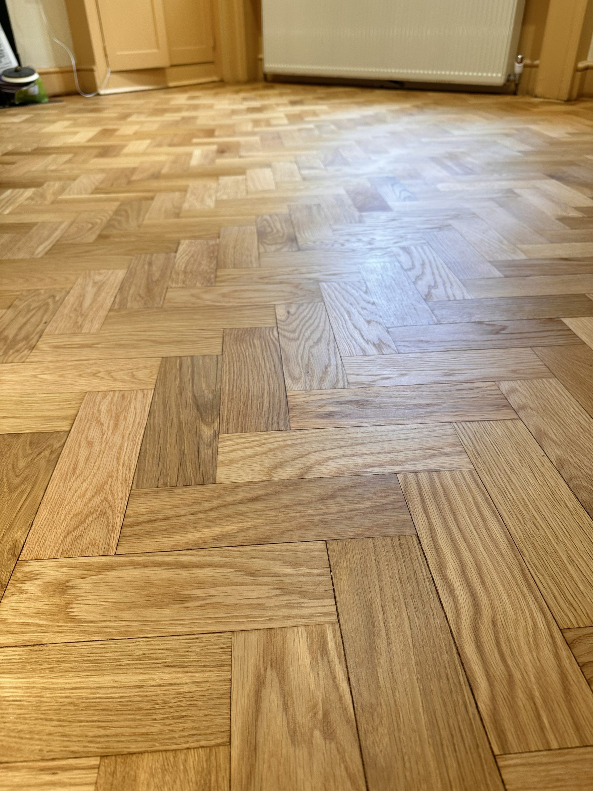 Low-angle detail of restored oak parquet flooring in Angel, London