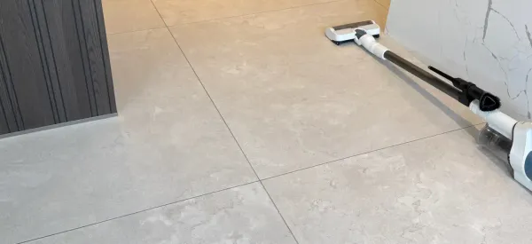 Bright and spotless light grey tiled floor with vacuum cleaner, showcasing professional tile cleaning results in a modern home