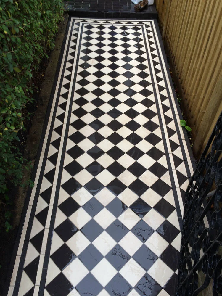 Victorian tiled pathway in London with a black and white checkered pattern, showcasing elegant diamond designs and freshly cleaned surfaces