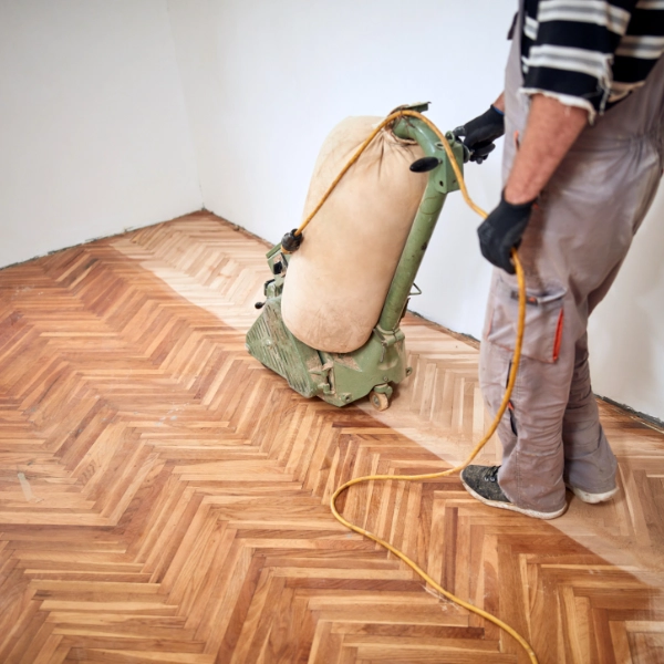 Technician sanding parquet floor in a London home using dust-free machine — wood floor sanding near me