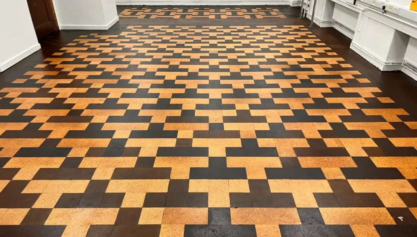Completed cork floor restoration in a London school, showcasing a seamless geometric pattern after sanding, staining, and lacquering.