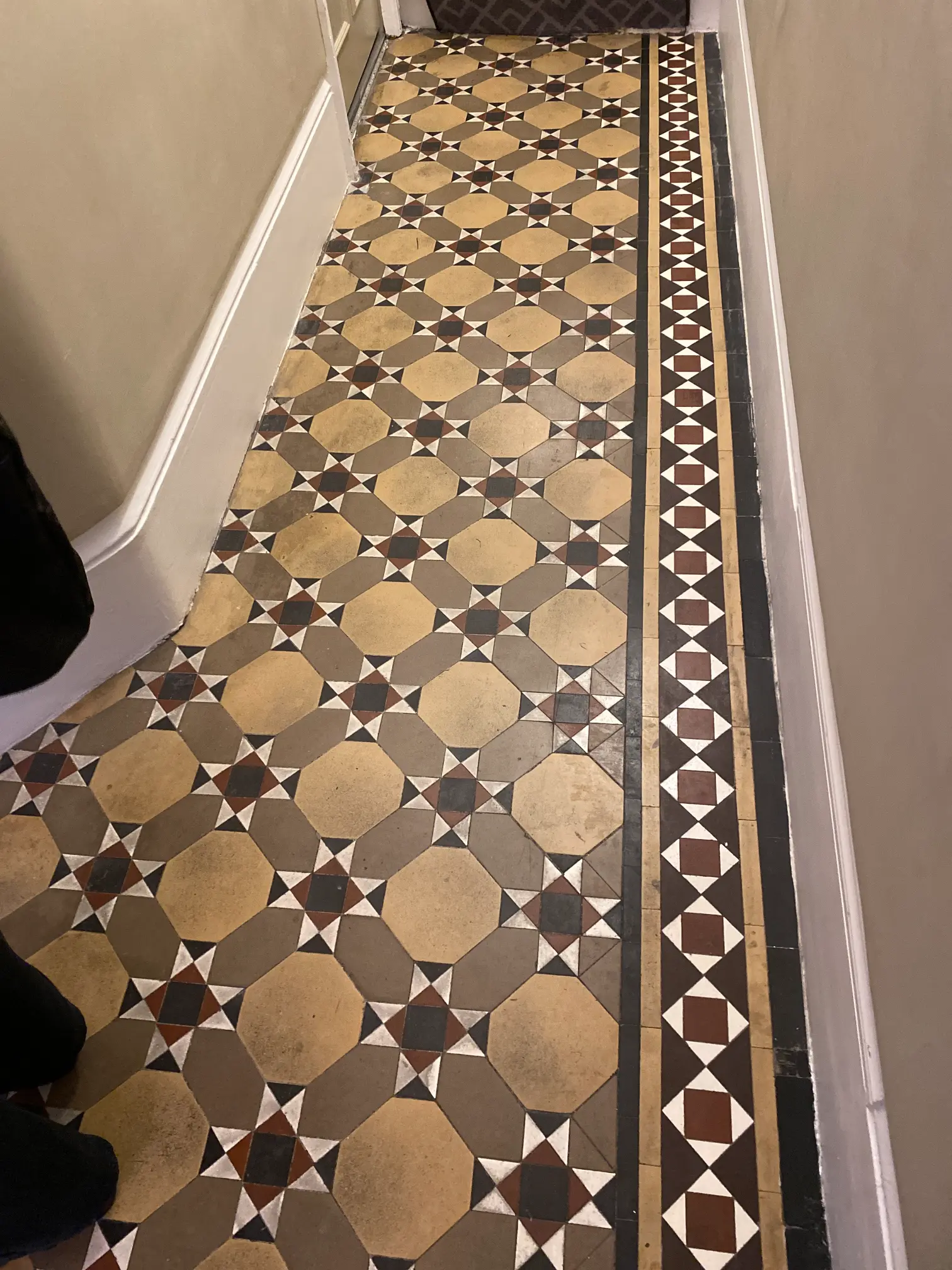 Victorian tiles in Kensington showing signs of wear, dirt, and dull colours before the cleaning and restoration process.