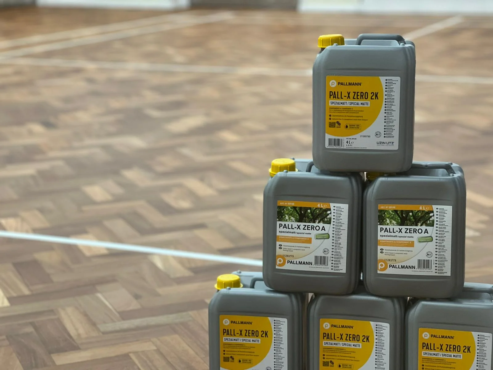 Stack of Pall-X Zero cans on a parquet school hall floor during a restoration project in Caterham.
