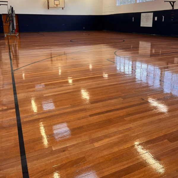 Freshly varnished wooden sports hall floor with a high-gloss finish, providing durable protection and enhanced aesthetics.