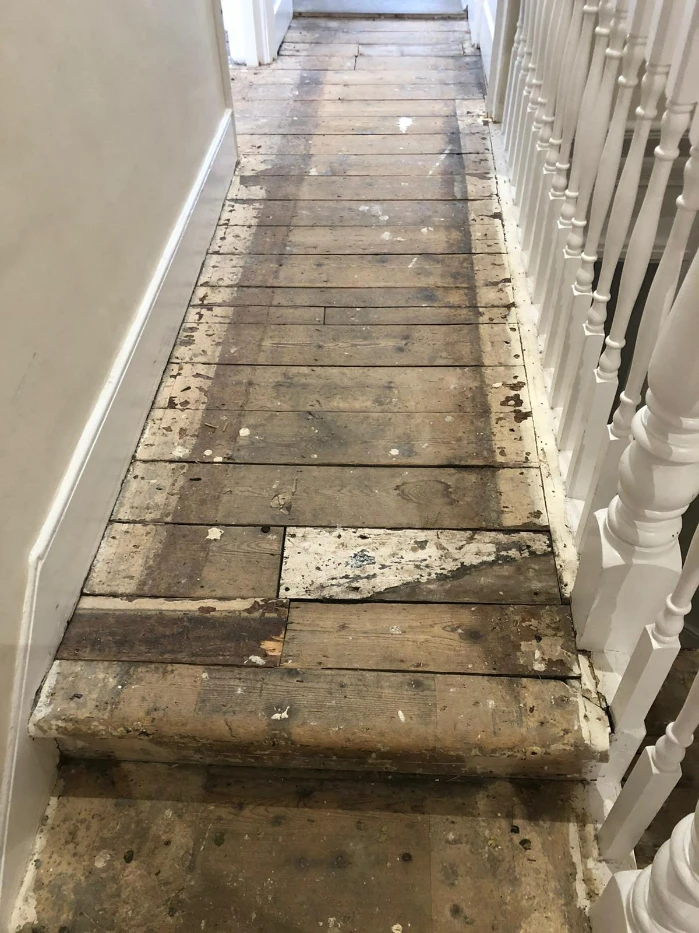 Damaged pine floorboards in a London hallway