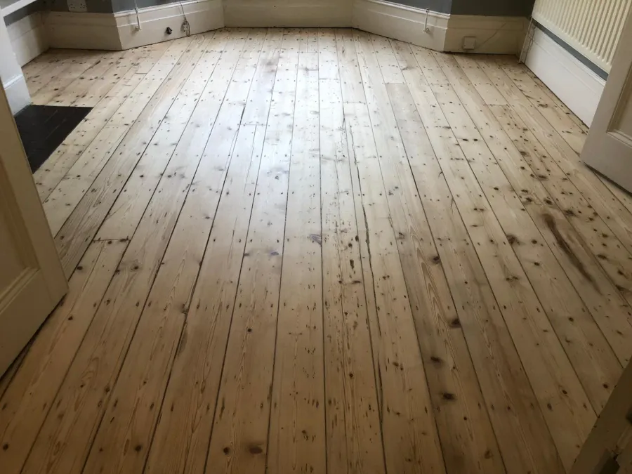 Sanded pine floorboards in a London home, showcasing a smooth, natural wood finish with visible knots and grain patterns.