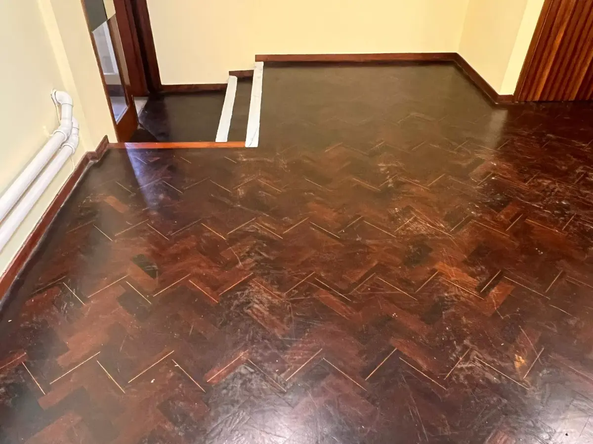 Close-up of damaged Wenge parquet floor showing surface wear and traffic marks