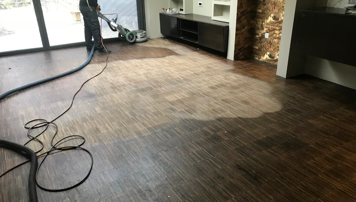 A floor sanding expert restoring a fumed oak floor in Wandsworth, London. The image captures the transformation process, with the sanded area revealing the natural wood colour while removing scratches and surface imperfections.
