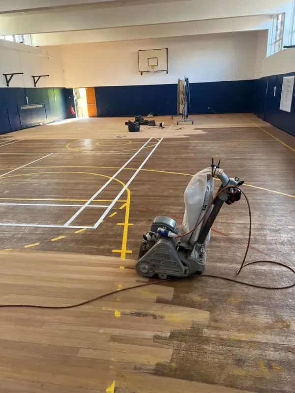 Dust-free floor sanding machine restoring a large wooden sports hall floor