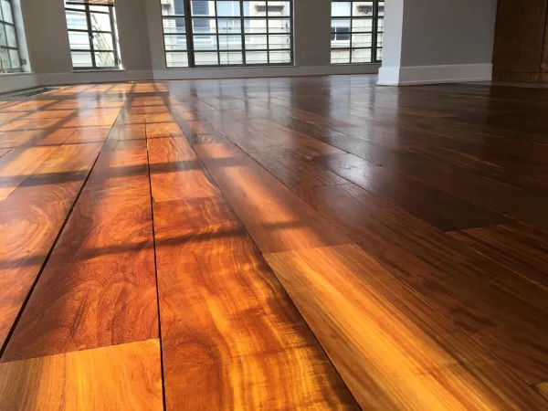 Close-up of a beautifully finished Ipe Lapacho wood floor with a warm, smooth surface in a London property, reflecting natural light through large windows.