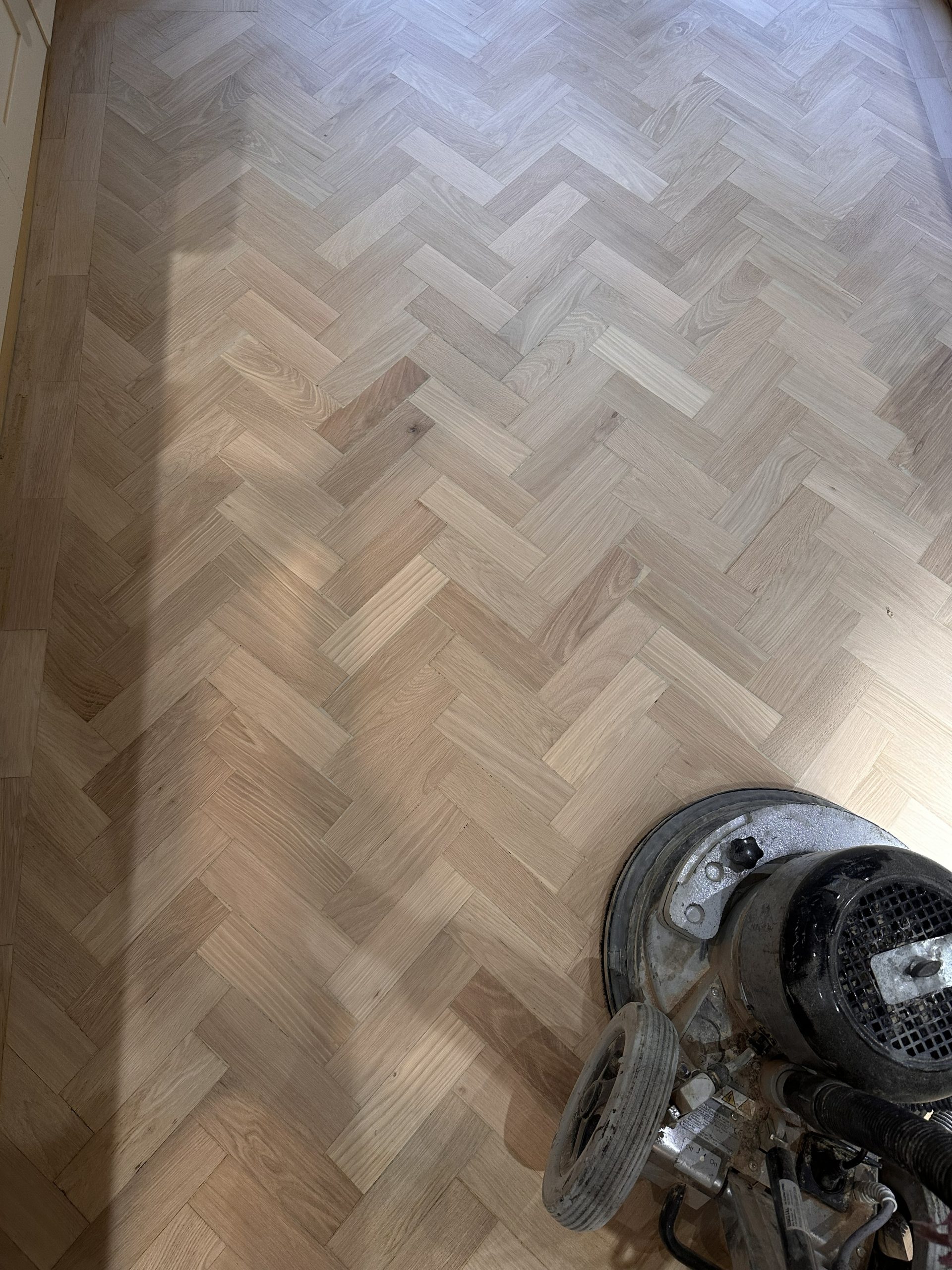 Sanding machine on oak parquet flooring during restoration in Angel, London