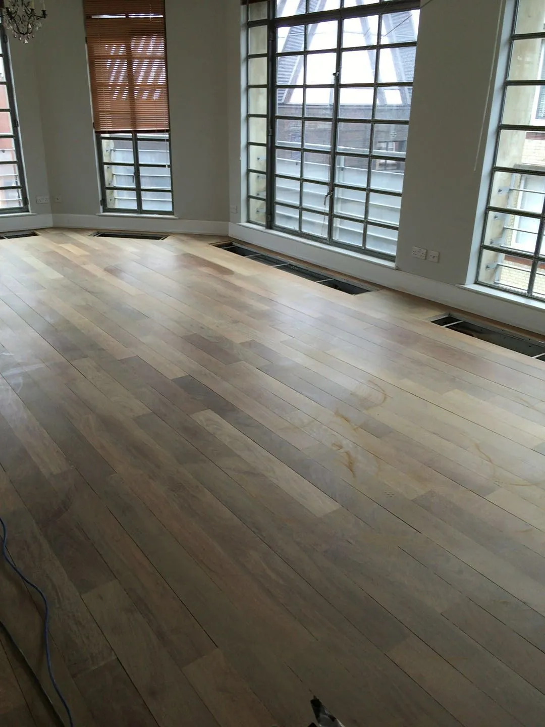 Initial sanding stage of an Ipe Lapacho wood floor in a London property, revealing the natural, raw wood surface with a smooth finish in preparation for priming.