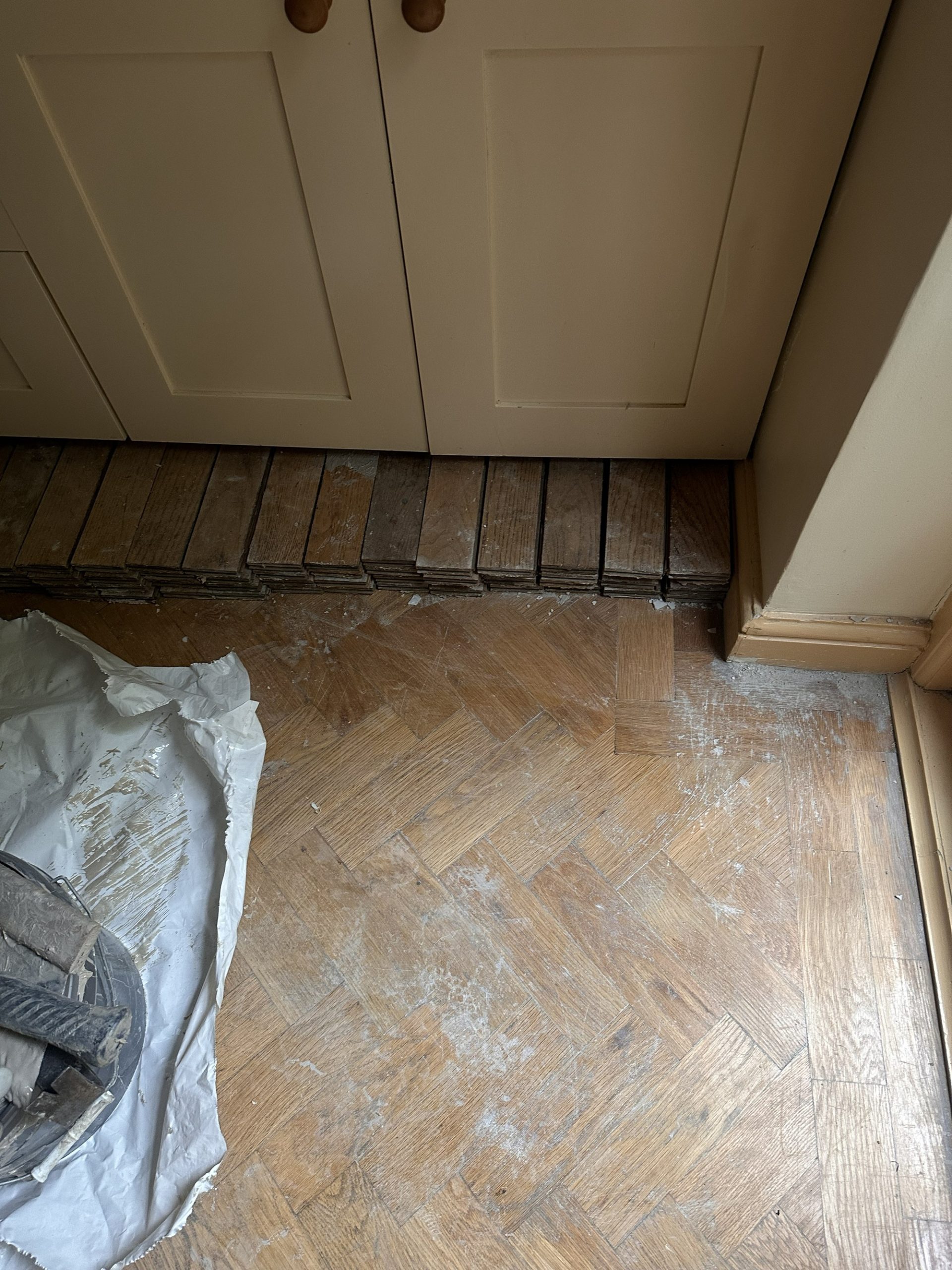 Oak parquet kitchen floor at threshold during sanding and restoration in Angel, London
