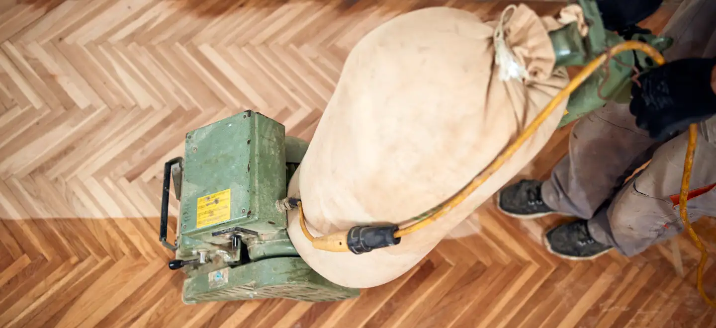 Herringbone wood floor partially sanded showing DIY vs professional sanding results