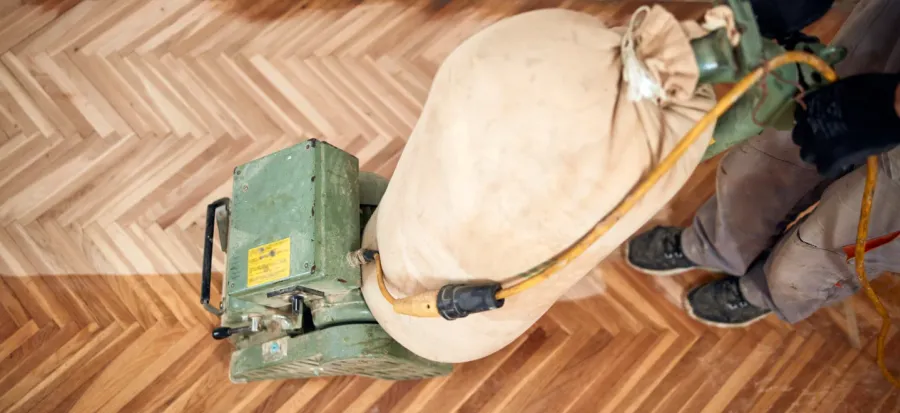 A close-up shows a parquet floor being sanded. A professional drum sander is used for wood floor restoration in London