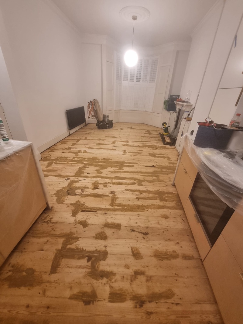 Wide room view of pine floor restoration work in London kitchen and living area