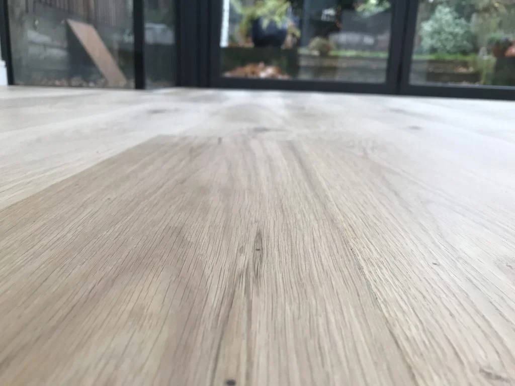 Close-up view of an oak floor in Dulwich Village during the sanding process, revealing the raw wood surface.