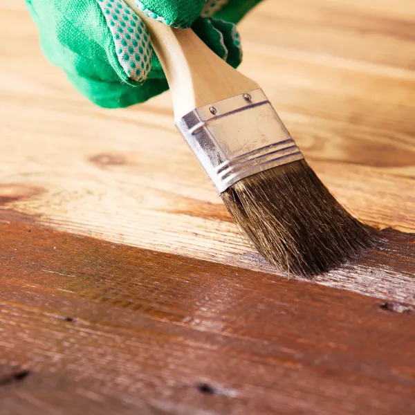Applying custom wood stain to a floor with a brush, showing precision colour matching in Chelsea home
