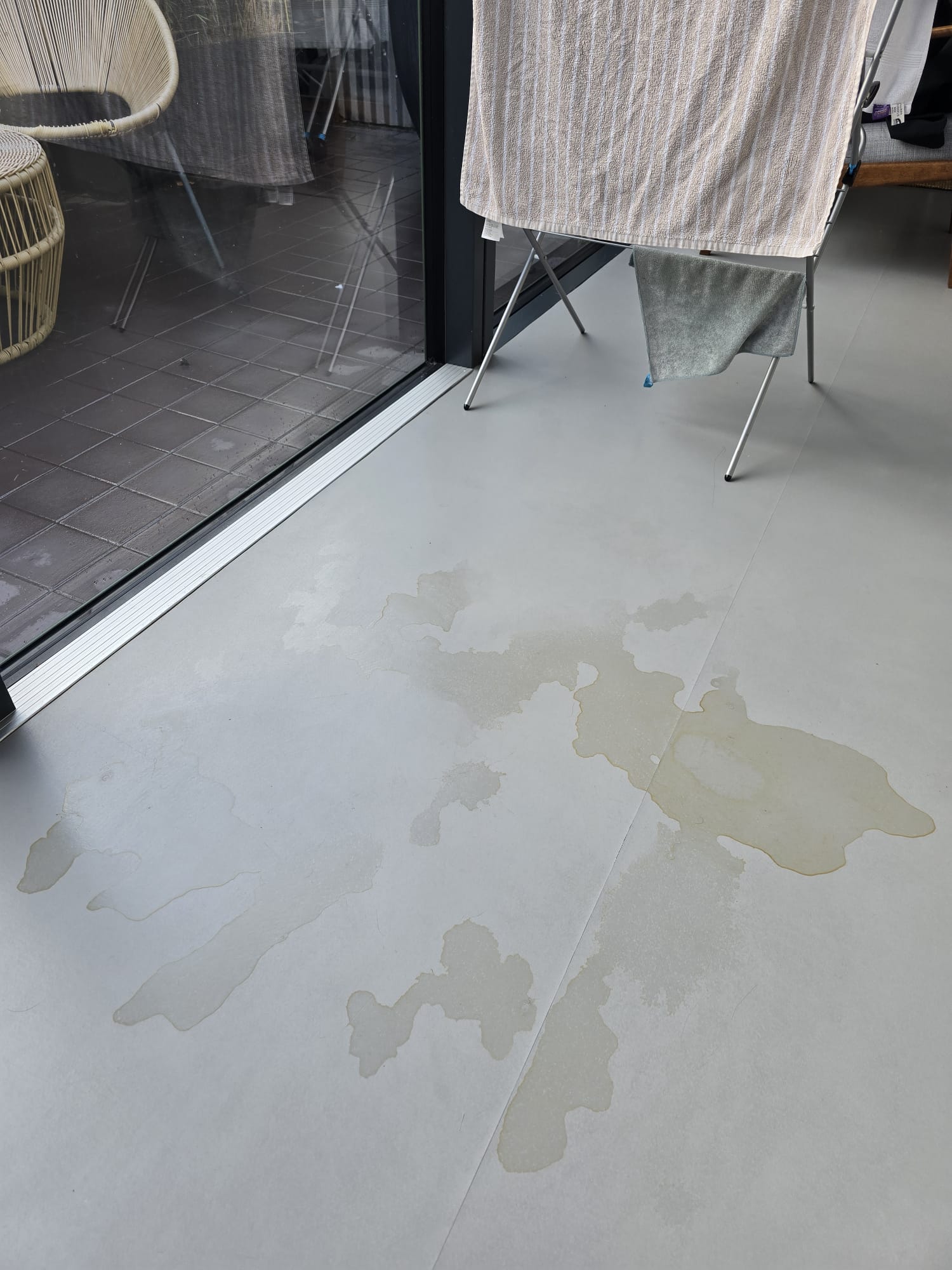 Moisture damage visible on a grey resin floor near glazed doors in Kennington, South London