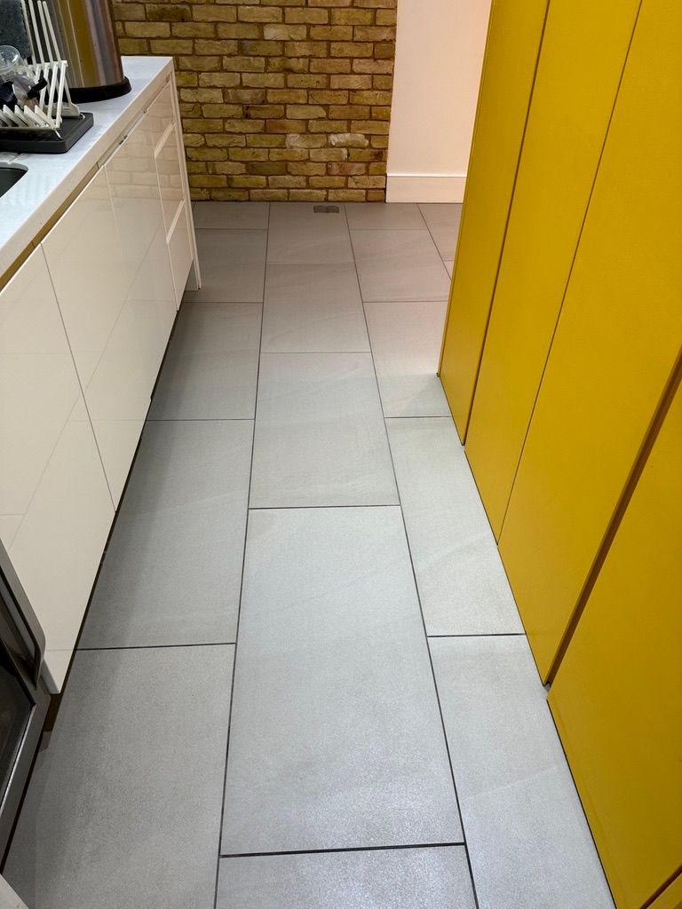 Grey ceramic tile floor after professional tile floor cleaning in a London kitchen walkway.