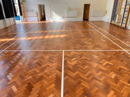 Herringbone teak school floor with fresh sanding and badminton court markings in Caterham