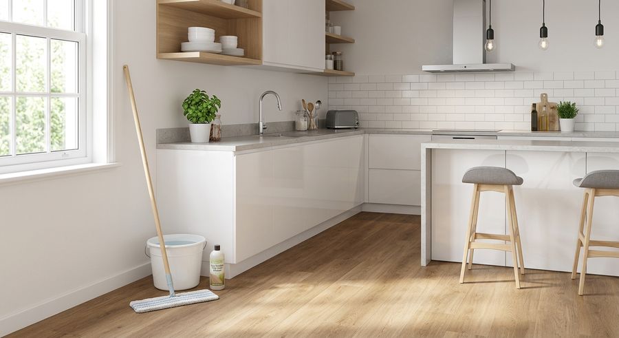 Mop and bucket resting against a kitchen island beside light wood-look vinyl plank flooring in a London home