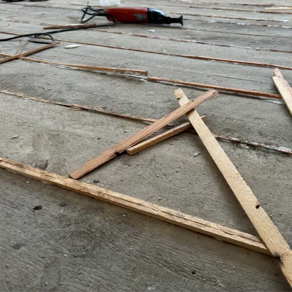 Floorboard repair in progress in London with wooden slivers being inserted between old boards to fill gaps