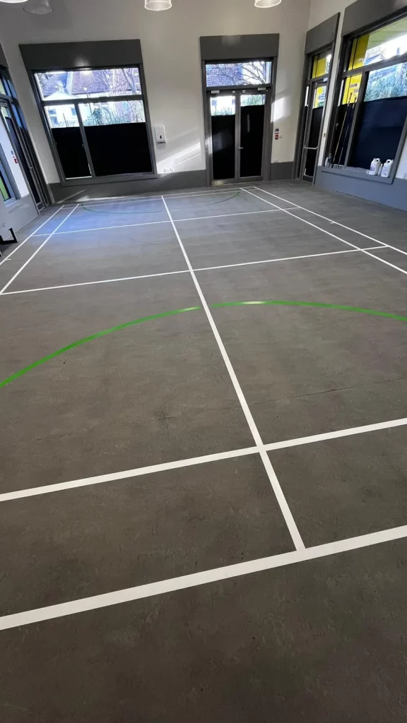 Completed sports court floor restoration in Stratford with white and green line markings.