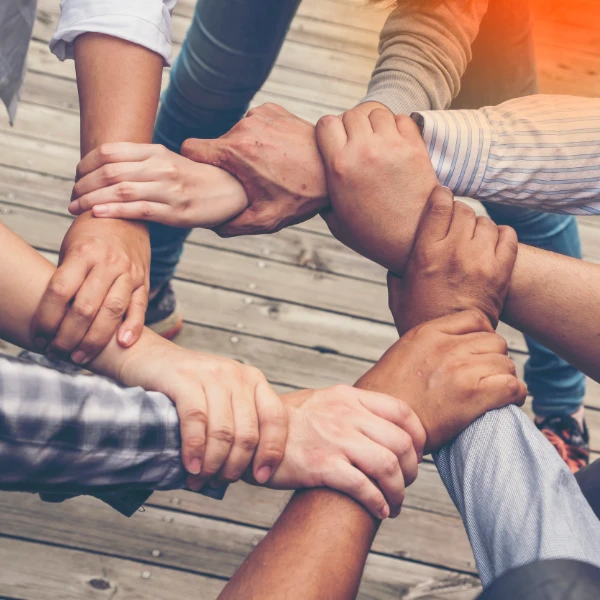 Close-up of diverse hands joined together in unity, symbolising trust and teamwork in floor restoration services