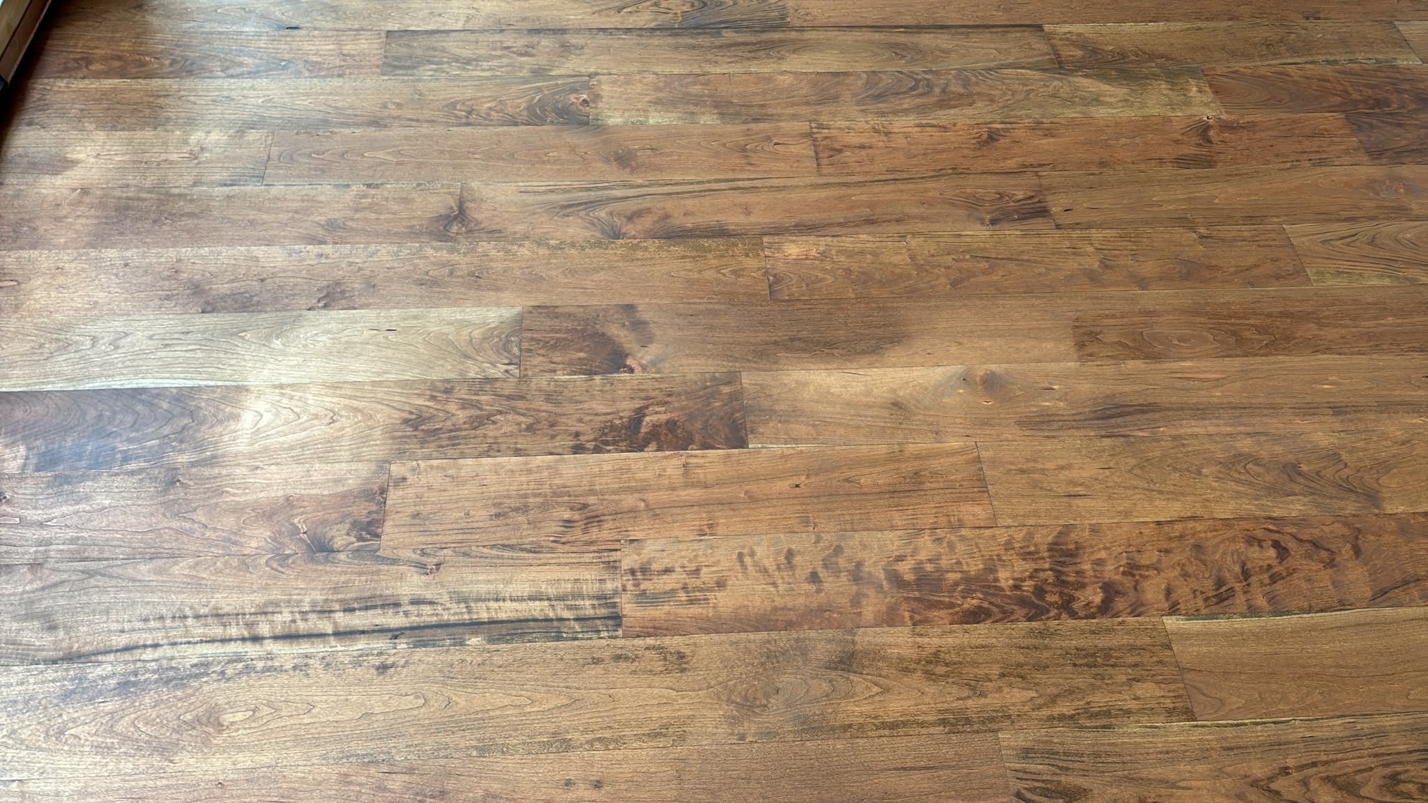 Close-up of mid-brown hardwood floorboards with varied grain and darker figuring