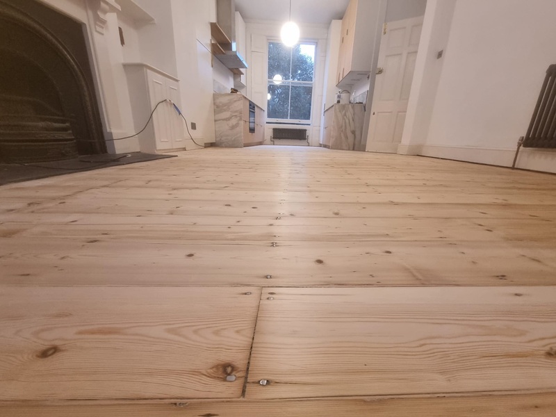 Wide view of Victorian pine floorboards prepared for sanding in London period property