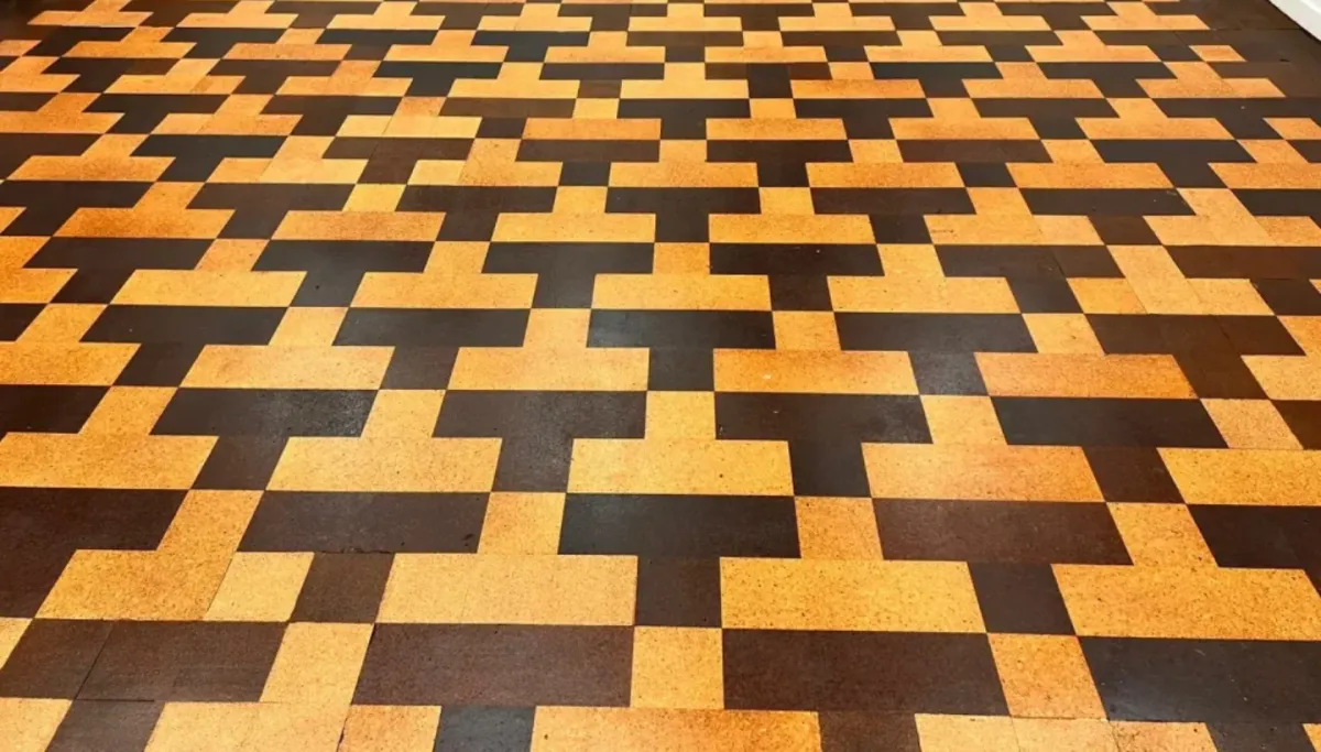 Restored cork floor in a London school featuring a geometric pattern after professional sanding, staining, and lacquering.