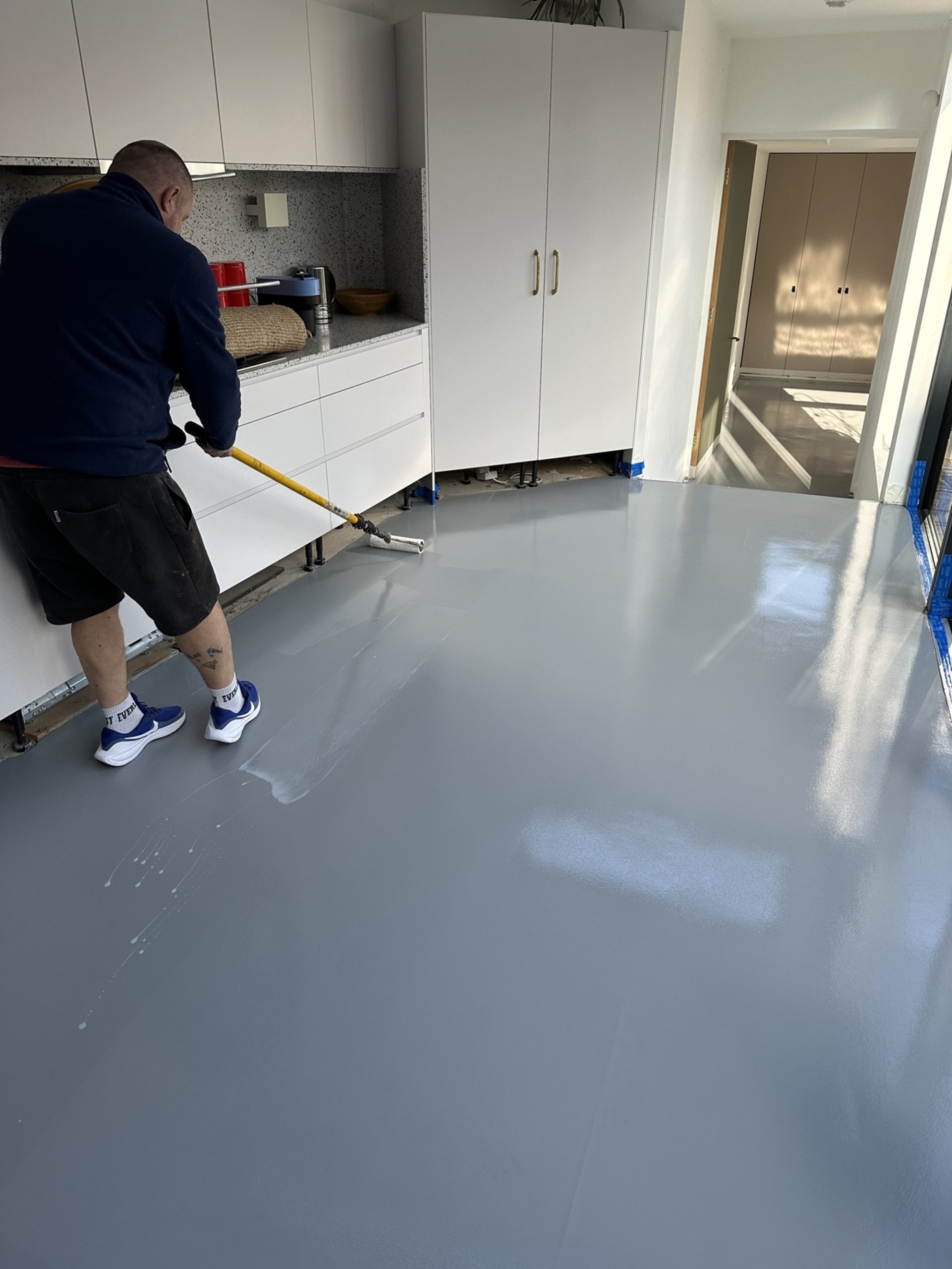 Grey resin floor coating being applied in a kitchen in Kennington, South London