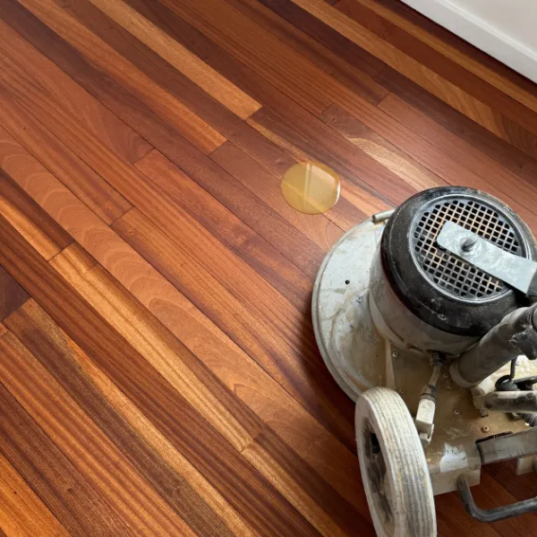 Close-up of a floor sanding machine being used on rich hardwood flooring in a Kensington property