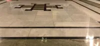 Close-up of a polished natural stone floor with dark inlay, demonstrating proper cleaning and care techniques.