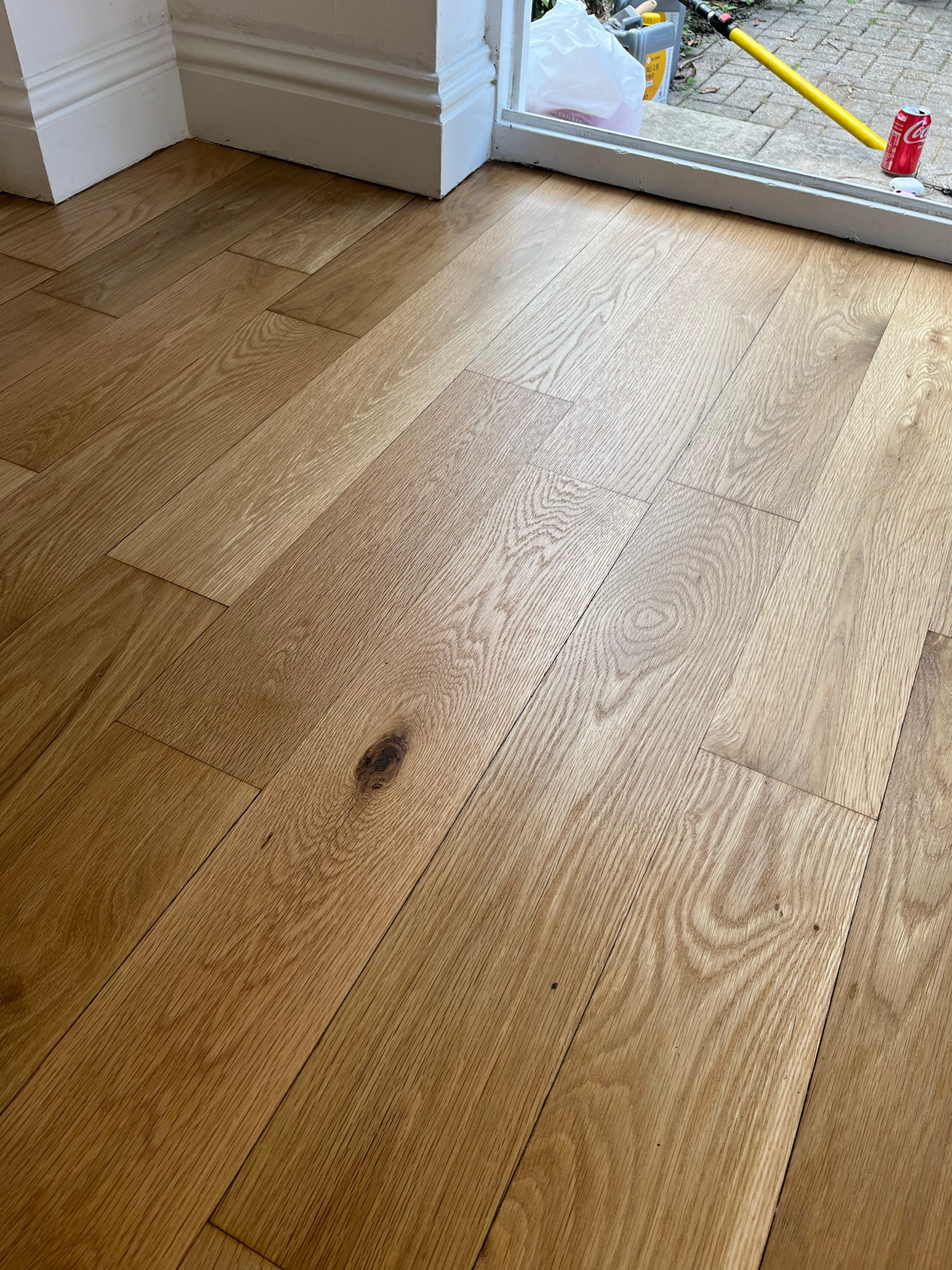 Close-up of natural oak planks with a dark knot and strong grain pattern near a doorway threshold.