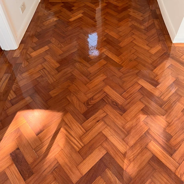Freshly refinished parquet floor with a rich, glossy finish, showcasing depth, warmth, and professional restoration.