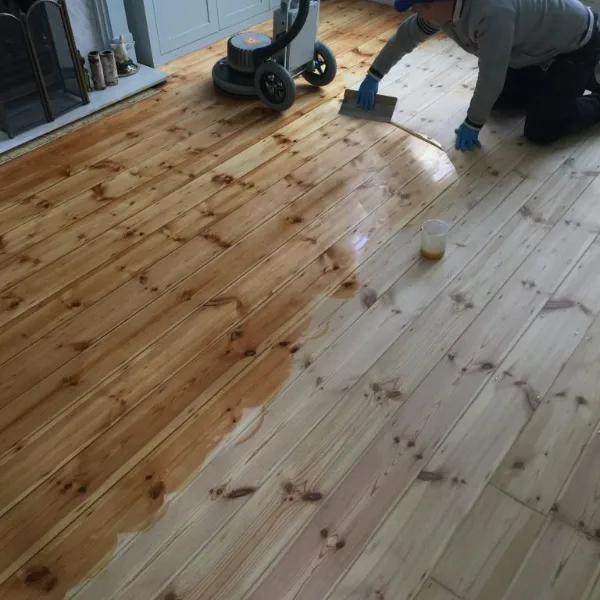 Specialist applying finish to sanded Victorian floorboards in a London period home
