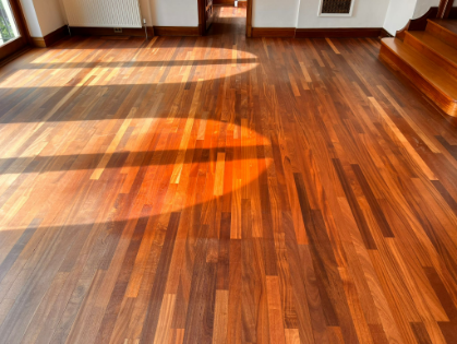 Restored teak floor in Whetstone showcasing vibrant tones and a smooth, polished finish with natural light enhancing its beauty.