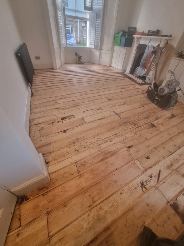 Professional floor sanding removing old finish from Victorian pine floorboards in London home