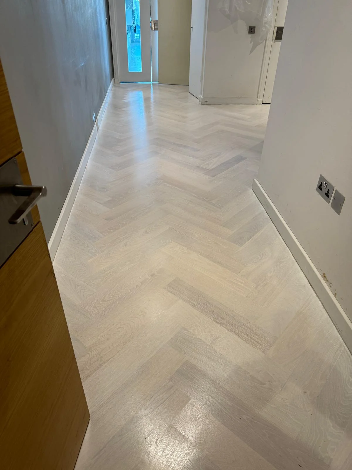 Herringbone wood floor in London finished with a Scandinavian-style whitewashed effect, showcasing a light and elegant appearance.