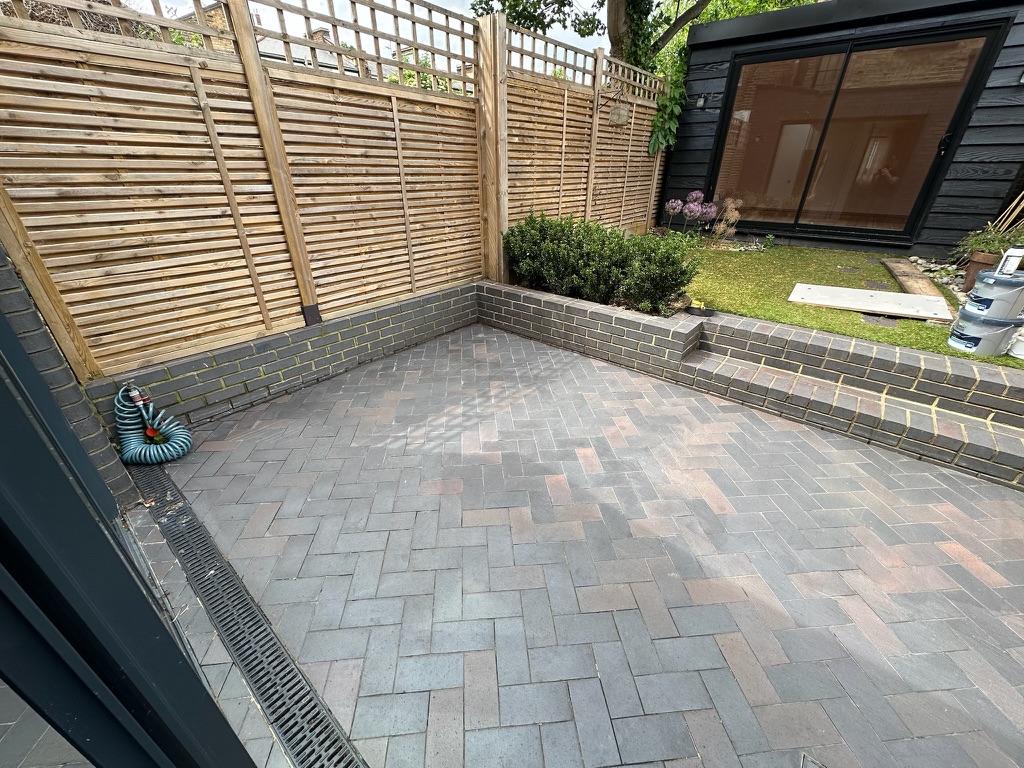 Kentish Town blue brick ceramic patio floor cleaning with garden and fencing.