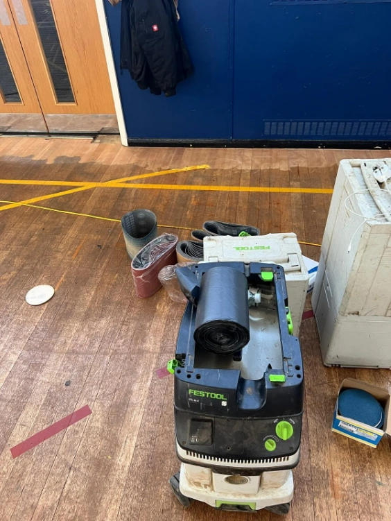 Preparation tools for comprehensive sports hall floor restoration in Croydon, showcasing the initial phase of sanding and lining.