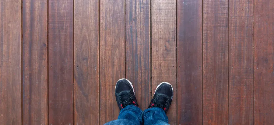 Person standing on a wooden floor, symbolising the decision-making process of hiring a floor restoration contractor.